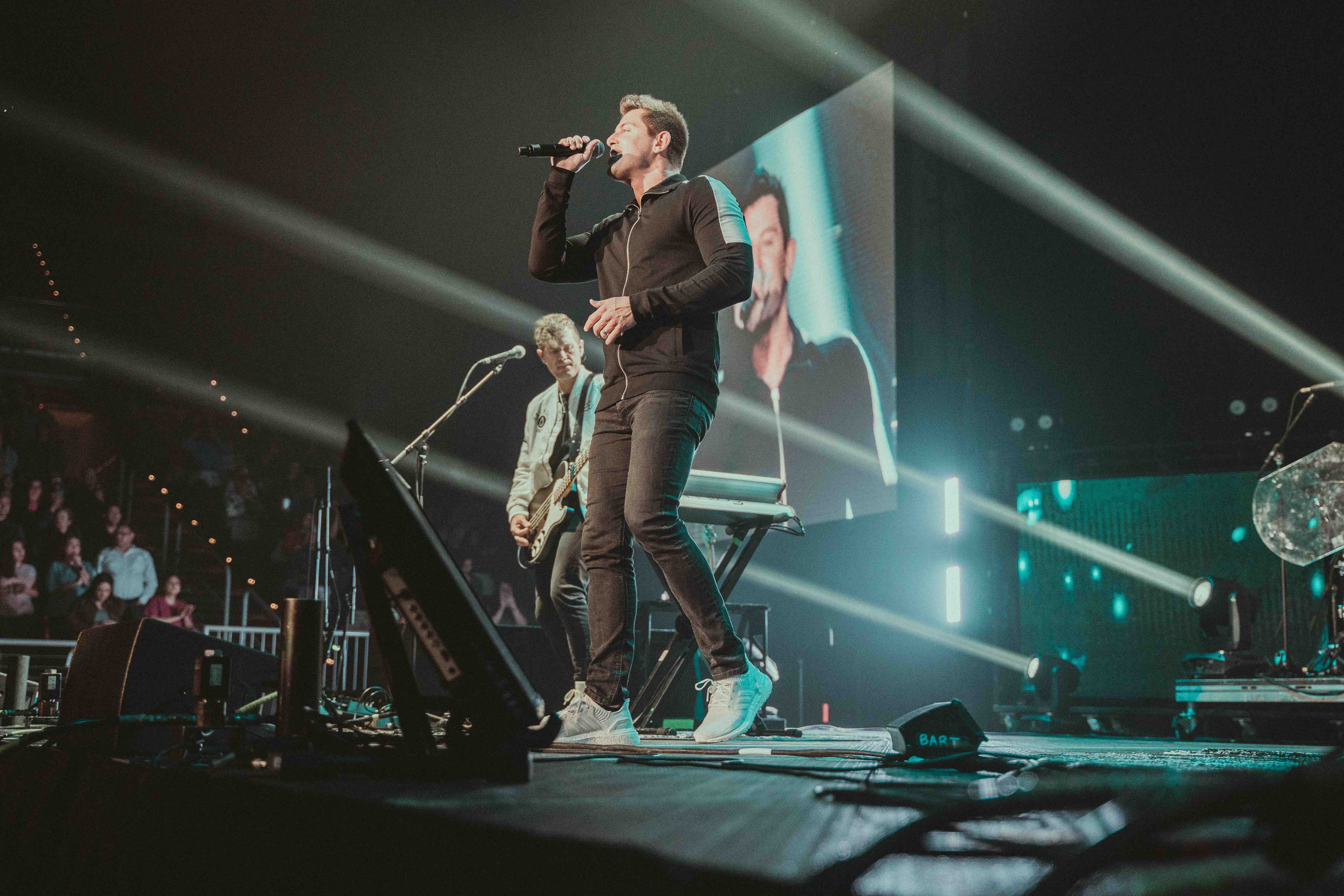 Jeremy Camp on a stage singing to a crowd during a concert.