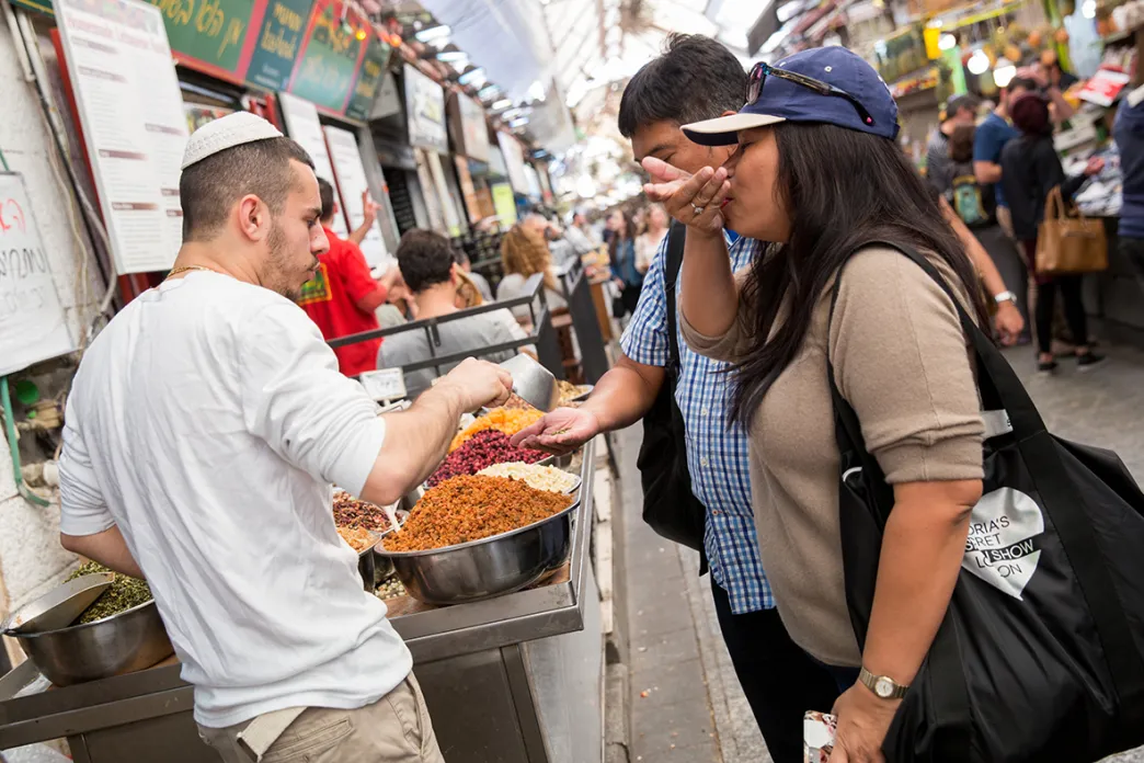 People tasting food at an open market area