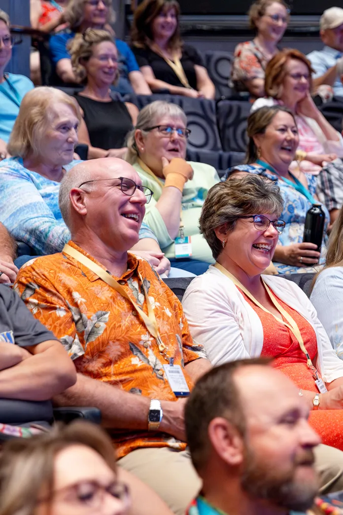 Laughing travelers sitting in an auditorium